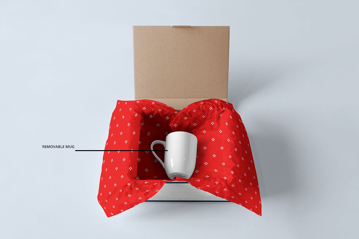 Top view of a packaging mockup featuring a brown mailing box, white mug, and red patterned wrapping paper.