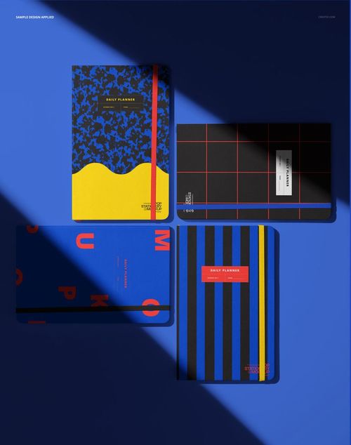 PSD mockup showing four leather planners with vibrant covers in various patterns, displayed from above on a blue surface.