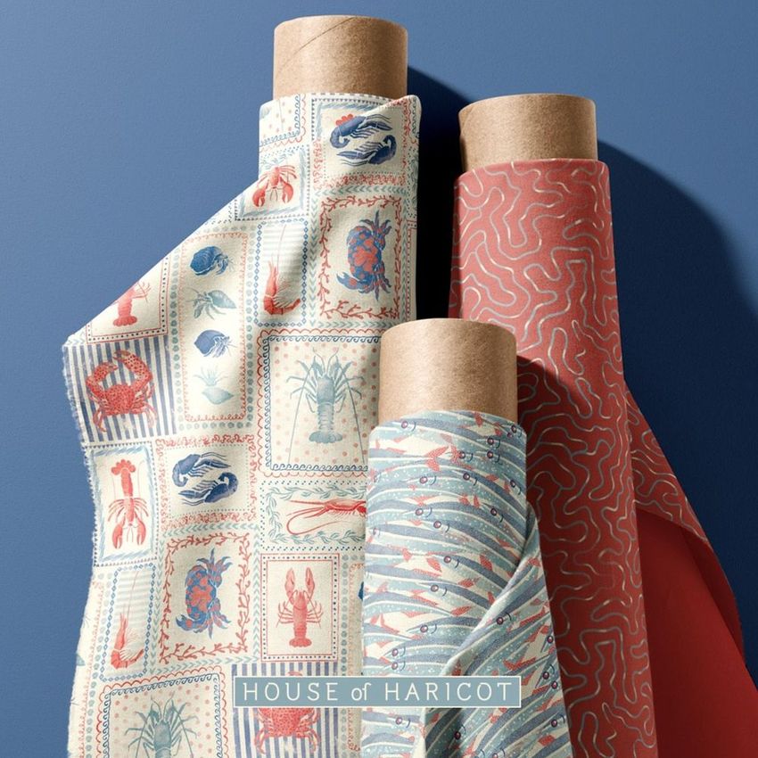 Fabric rolls mockup featuring three upright rolls with crustacean-themed patterns in red, blue, and cream tones on a blue background.