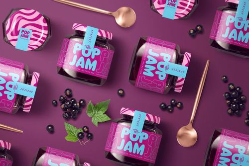 PSD mockup of blackcurrant jam jars with colorful labels, surrounded by blackcurrants and leaves on a purple background.