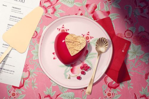 Valentines cake plate mockup featuring a heart-shaped cake, floral plate design, gold cutlery, and red napkin on pink fabric.