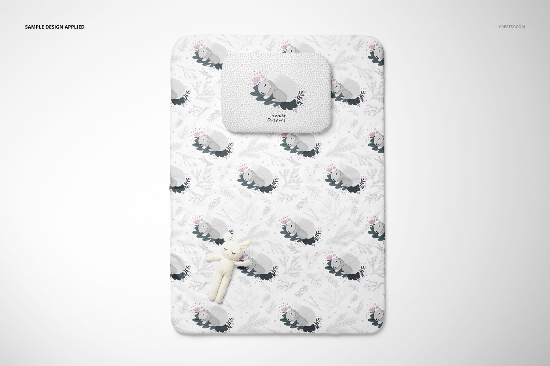 Double-sided baby bedding mockup with pillow and quilt, showing playful gray animal design on a white surface.