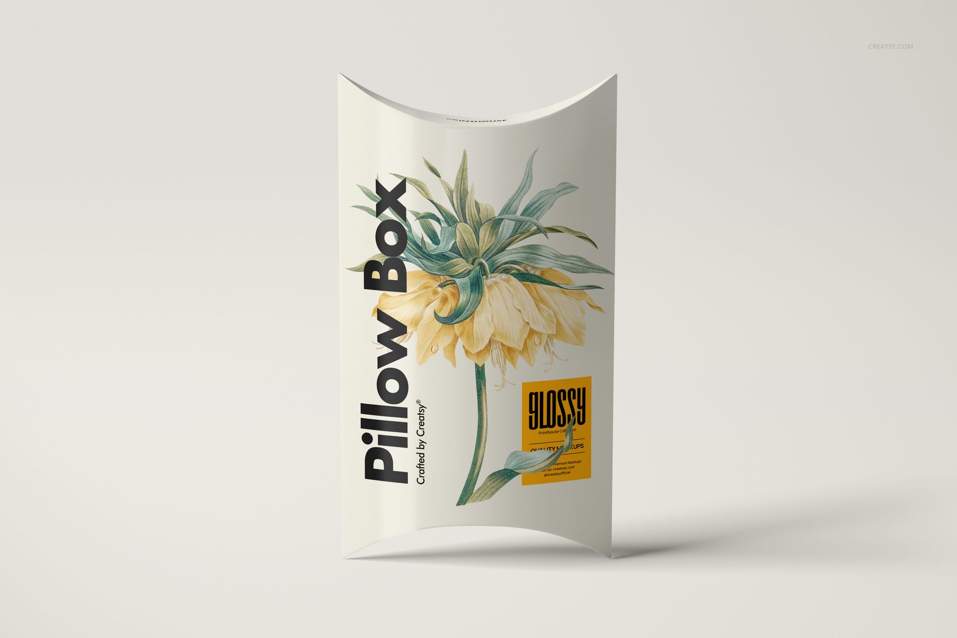 Front view of a glossy pillow box mockup featuring a yellow flower design and black lettering on a plain surface.