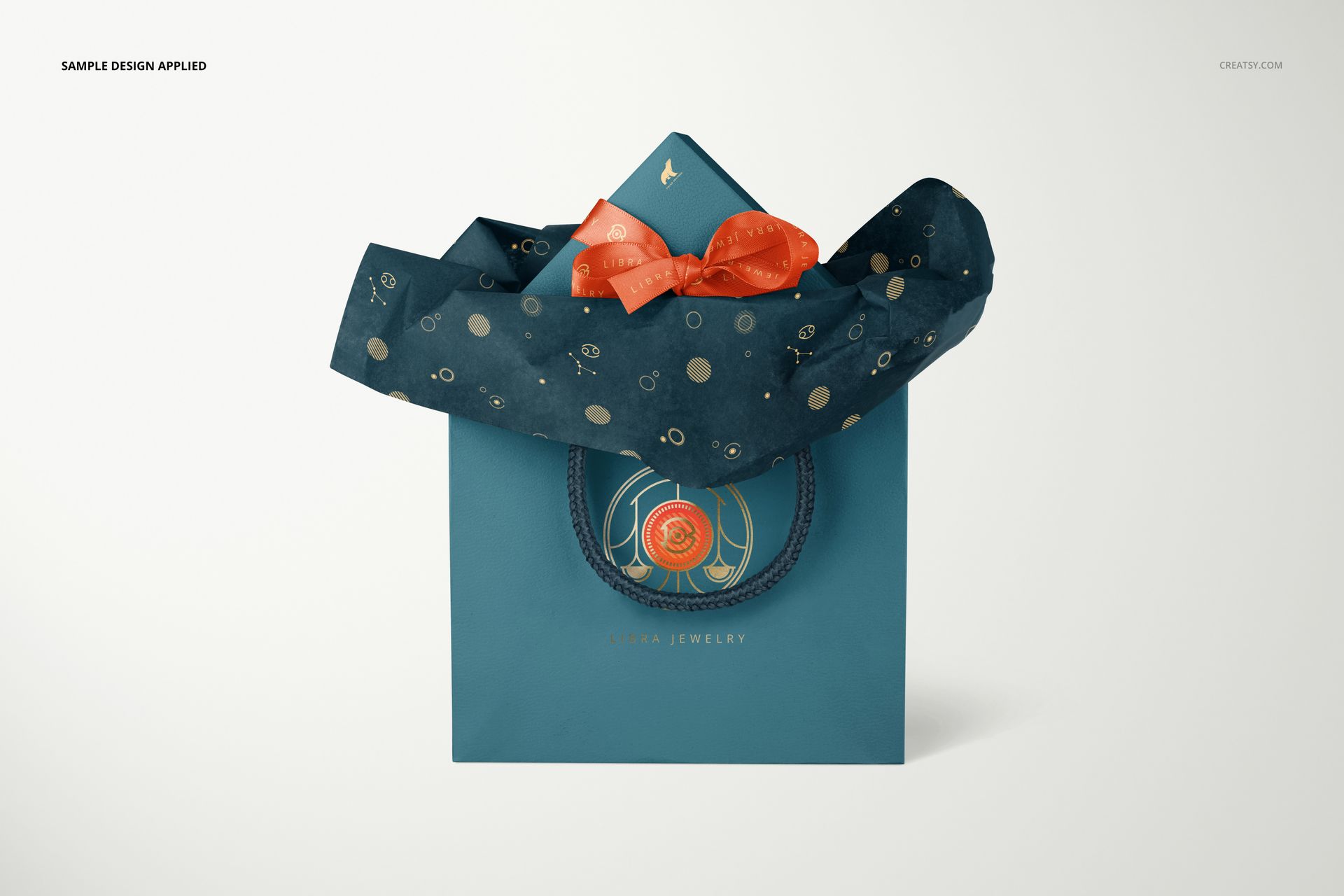 Jewelry box and bag PSD mockup featuring blue packaging, patterned tissue paper, and decorative orange accents in a studio setting.