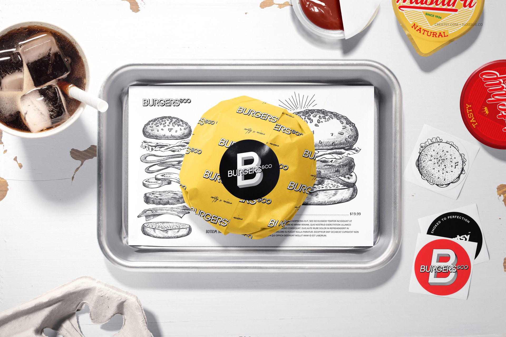 PSD mockup showing a burger in yellow wrapping paper with logo, set on a tray with illustrated food-themed paper.