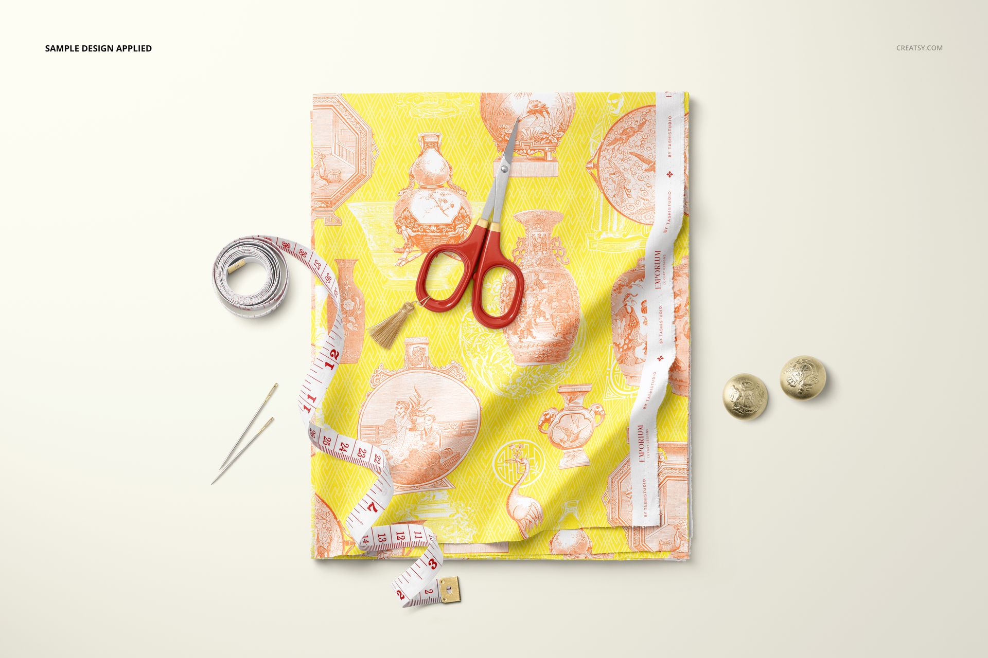 Top view of folded cotton fabric mockup featuring a vibrant yellow and pink design, surrounded by sewing accessories.