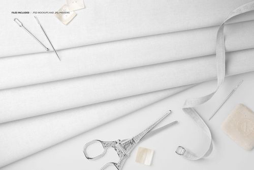 PSD mockup showing layered cotton fabric with tailoring items such as measuring tape, needles, and scissors arranged nearby.