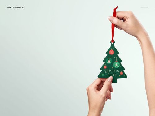Christmas PSD mockup showing a green tree ornament with colorful baubles and red string, presented in hand.