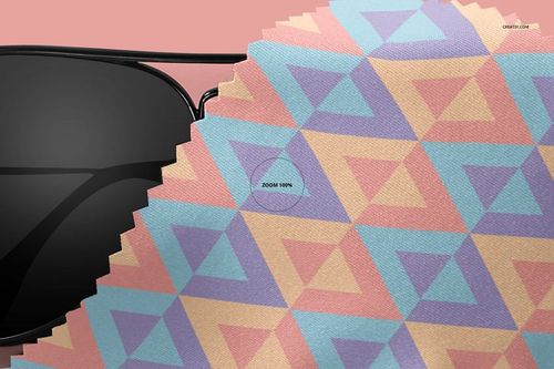 PSD mockup of a microfiber cloth with pink, purple, and blue geometric pattern, displayed near a pair of sunglasses.
