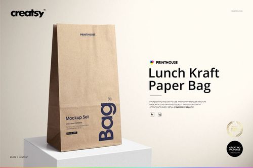 Front view of a standing kraft paper lunch bag with printed text, displayed on a light surface in a PSD mockup scene.
