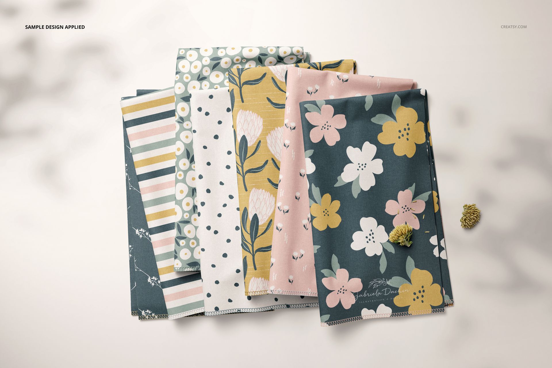 PSD mockup of several folded textile pieces with assorted pastel flower, stripe, and polka dot patterns, top perspective.