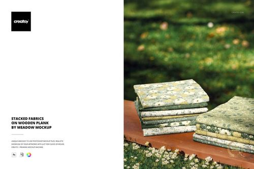 PSD mockup showing folded fabrics with various botanical prints, displayed on a wooden surface in an outdoor scene.
