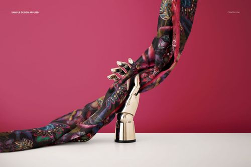 PSD mockup of a patterned habotai silk scarf wrapped around a shiny mannequin hand, set in front of a pink wall.