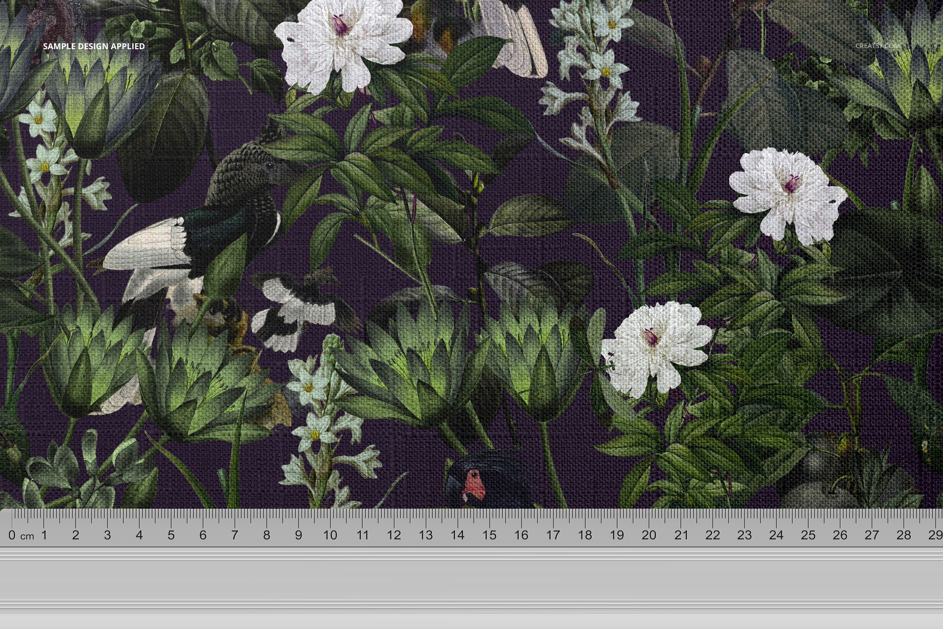 Botanical-themed tablecloth fabric mockup showing white flowers, lush green foliage, and birds on a purple backdrop.