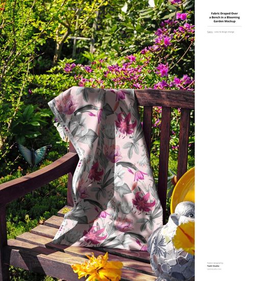 PSD mockup showing a flower print fabric casually placed on a wooden bench in a lush, sunlit garden setting.