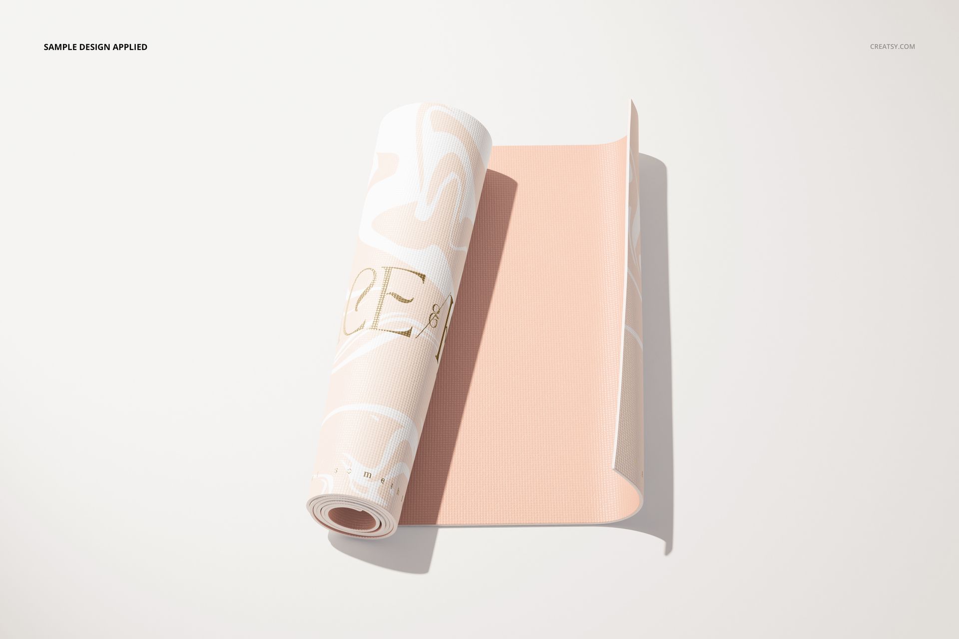Yoga mat mockup featuring a partially rolled mat in pastel pink tones with swirling designs, side perspective.