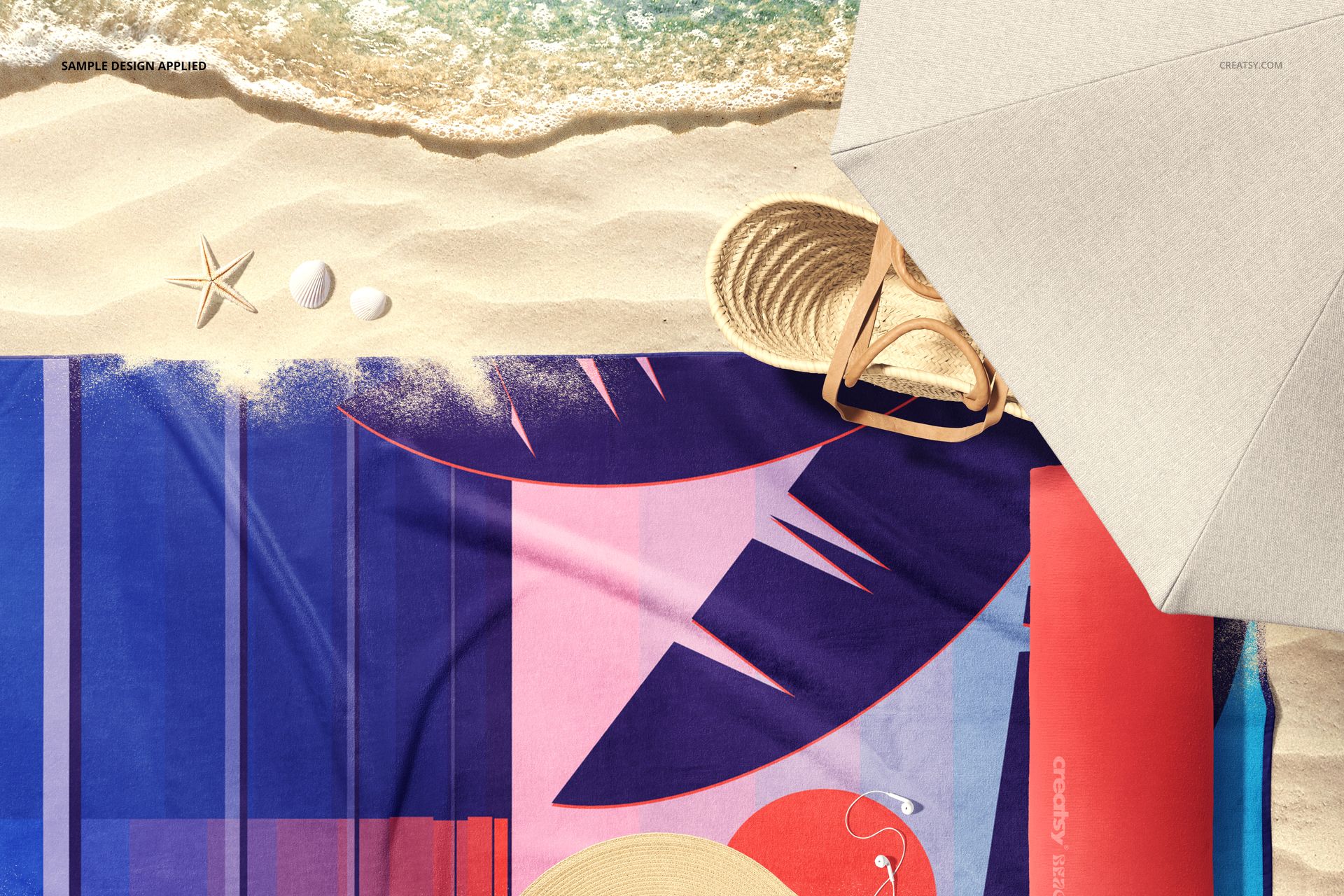 Seaside scene PSD mockup showing a rectangular towel with vibrant design on sand, next to umbrella and shells.