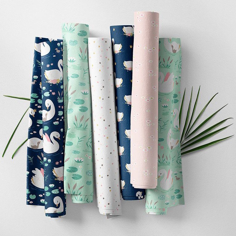 Fabric rolls mockup showing six patterned fabric rolls with swan, floral, and botanical designs in pastel and navy colors.
