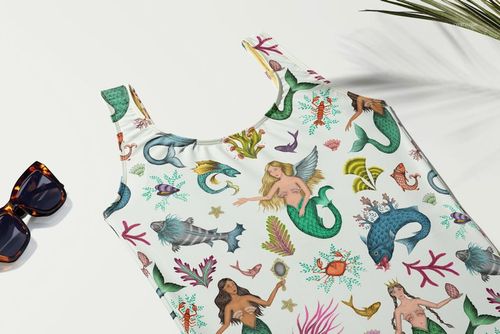 Swimsuit mockup featuring vibrant aquatic-themed patterns, shown flat with sunglasses and a palm leaf nearby.