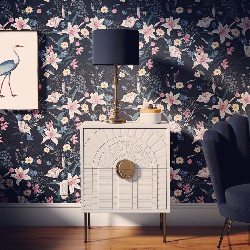 Drum lamp shade mockup on a gold and white lamp placed on a modern nightstand, with floral wallpaper and framed bird art.