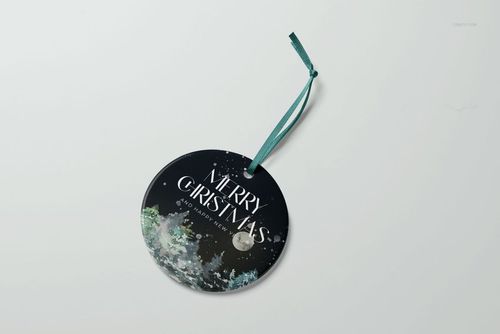 PSD mockup of a round Christmas ornament displaying a winter forest illustration and holiday message on a white background.