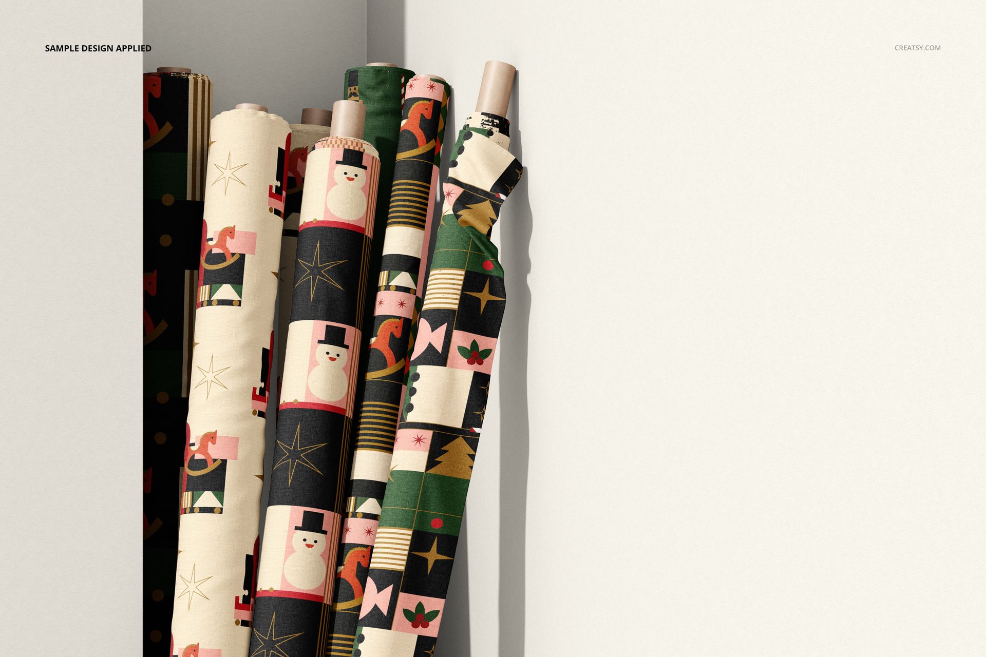 Fabric rolls mockup showing assorted Christmas patterns in green, black, and cream, positioned vertically by a corner.
