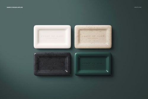 PSD mockup showing assorted hotel hand soap bars with embossed text, neatly placed side by side on a green surface.