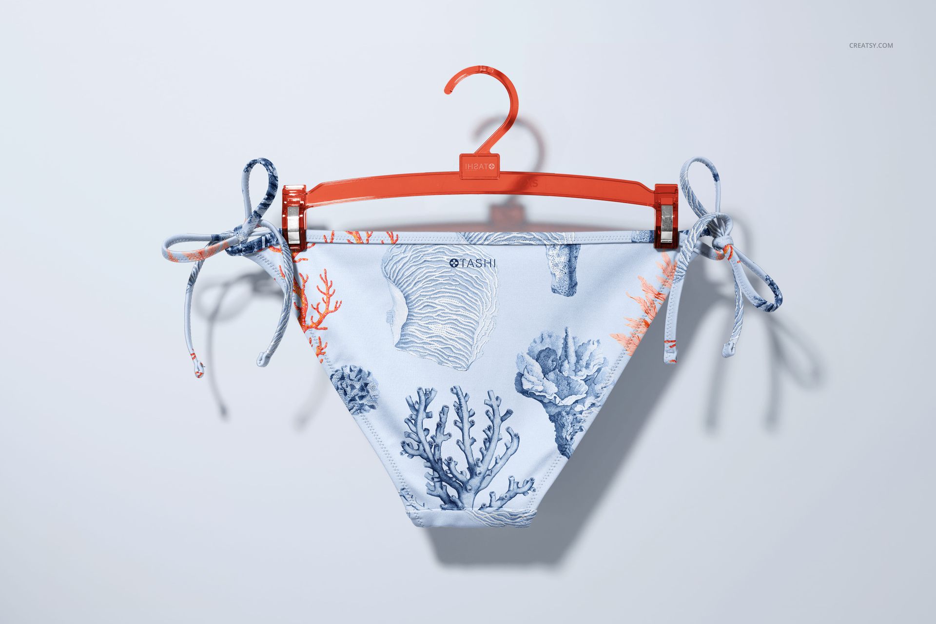 Front view of bikini bottom mockup with blue and orange coral pattern, displayed on an orange hanger against a light background.