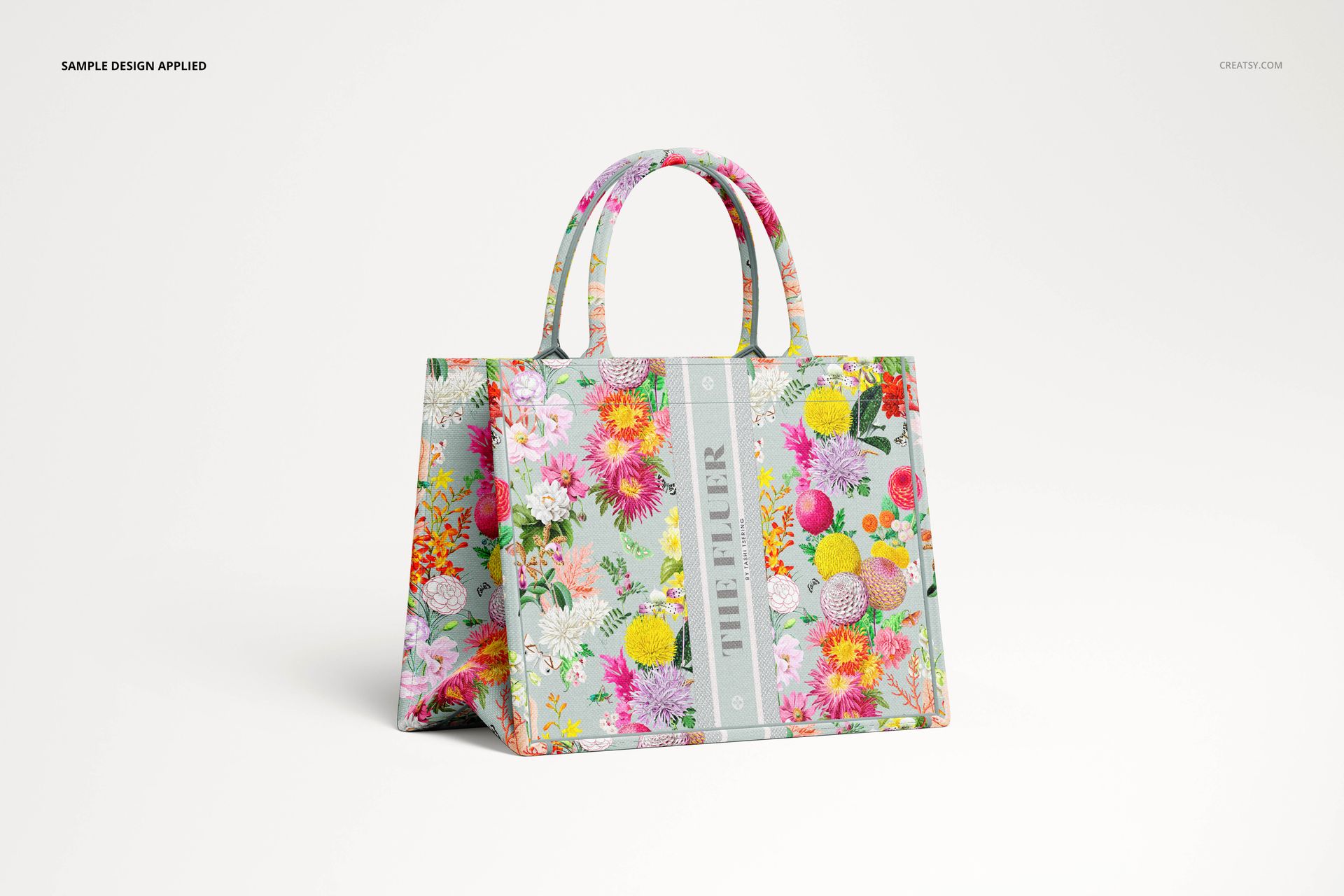 PSD mockup of a canvas tote bag displayed at an angle, decorated with vibrant multicolored flowers and green accents.