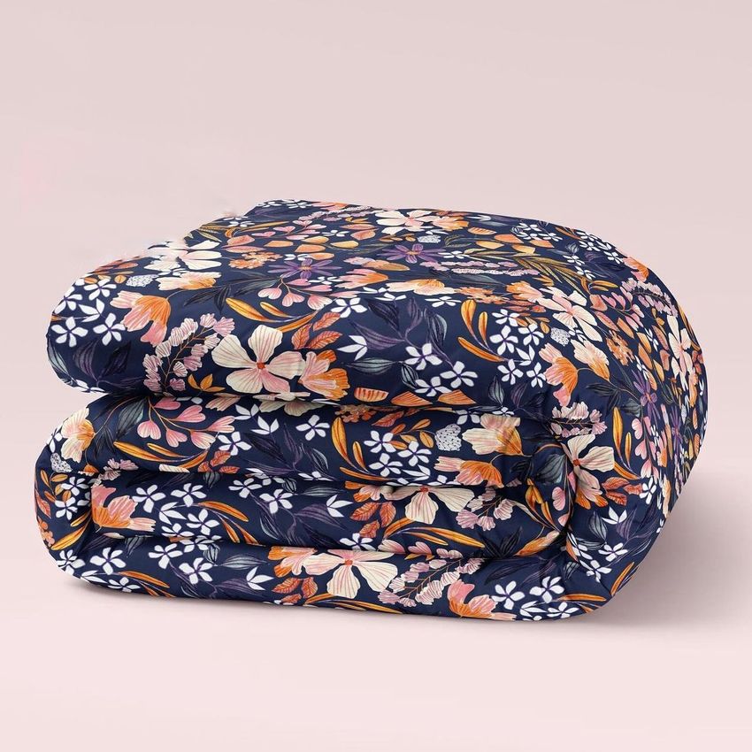 Microfiber comforter mockup featuring a folded comforter with a vibrant floral pattern on a dark background, set against a plain light backdrop.