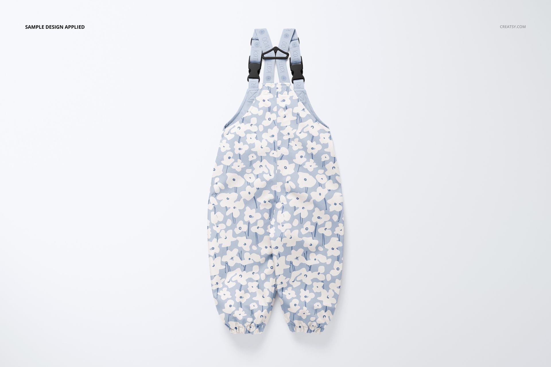 Front view of kids rainwear mockup featuring light blue overalls with white floral pattern on a plain background.