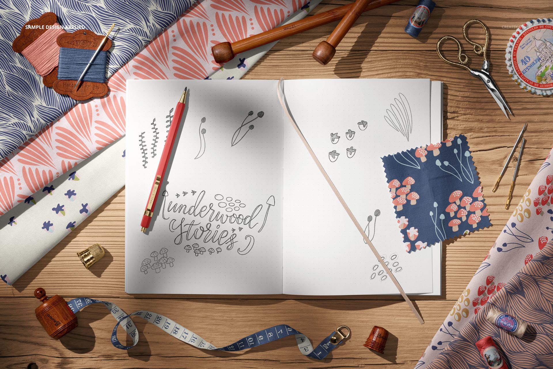 Top view of a creative desk with cotton fabric rolls, open sketchbook with botanical drawings, and sewing tools.