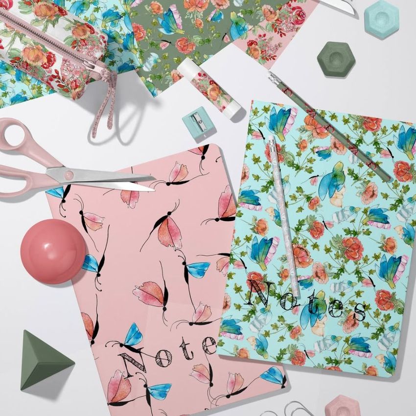 Stationery mockup featuring two classic A4 notebooks with butterfly and floral patterns, surrounded by scissors, pens, and paper props.