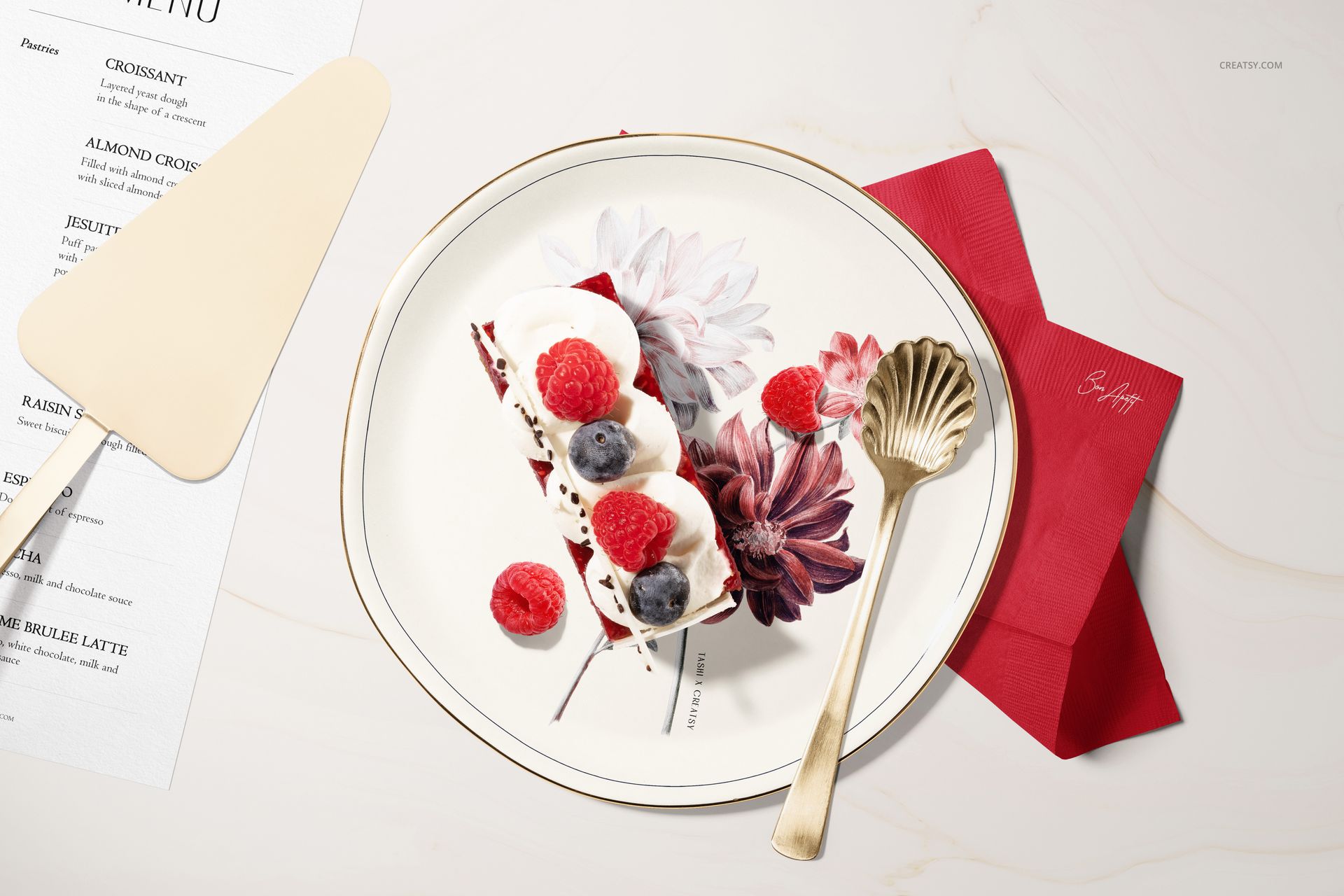 Pastry shop edition plate mockup displaying a decorated dessert, gold fork, and red napkin in a top view scene.