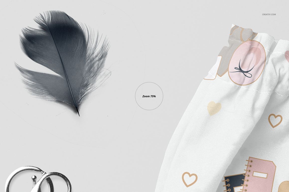 Front view of baby harem shorts mockup with pastel pattern, shown next to a black feather and silver rings on a light background.