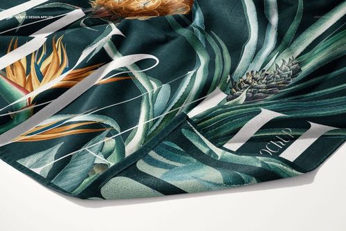 Detailed PSD mockup of a beach towel featuring botanical prints with lush green leaves and orange flowers on fabric.