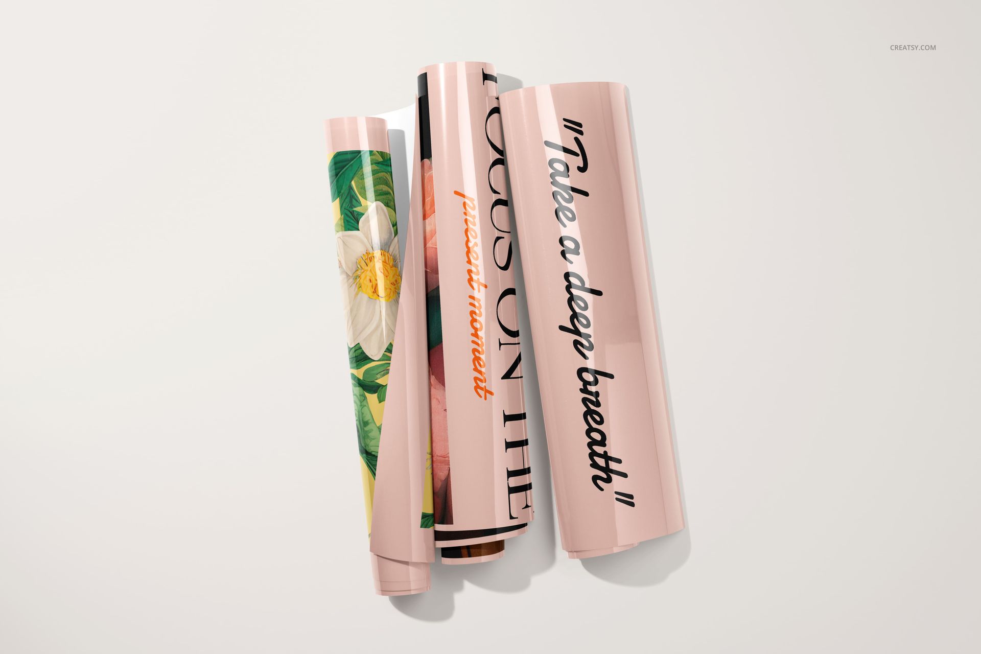 Four glossy PVC posters rolled up on a light surface, featuring floral artwork and bold black typography.