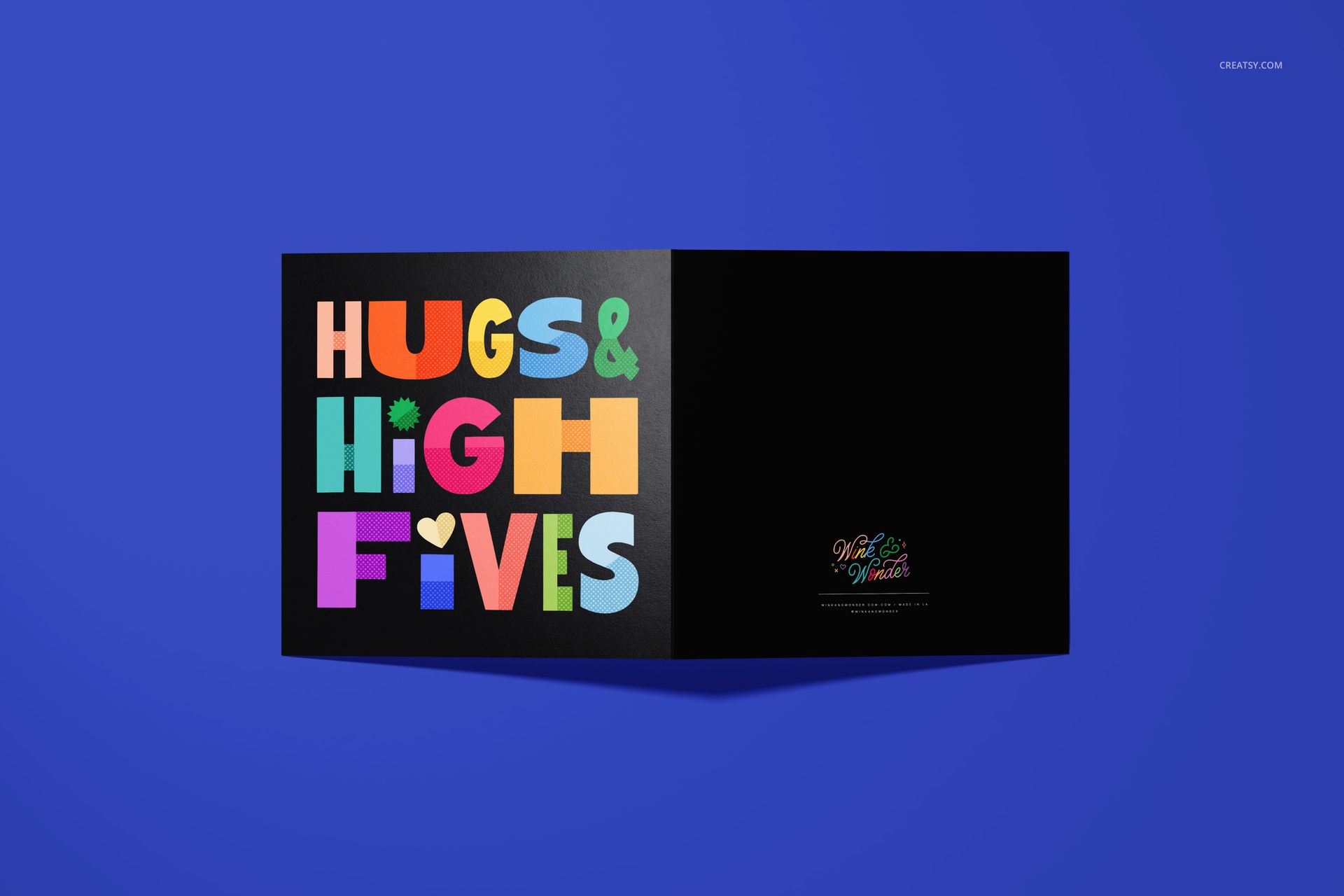 Square folded greeting card mockup featuring a colorful text design on the left and a plain black section on the right, top view.