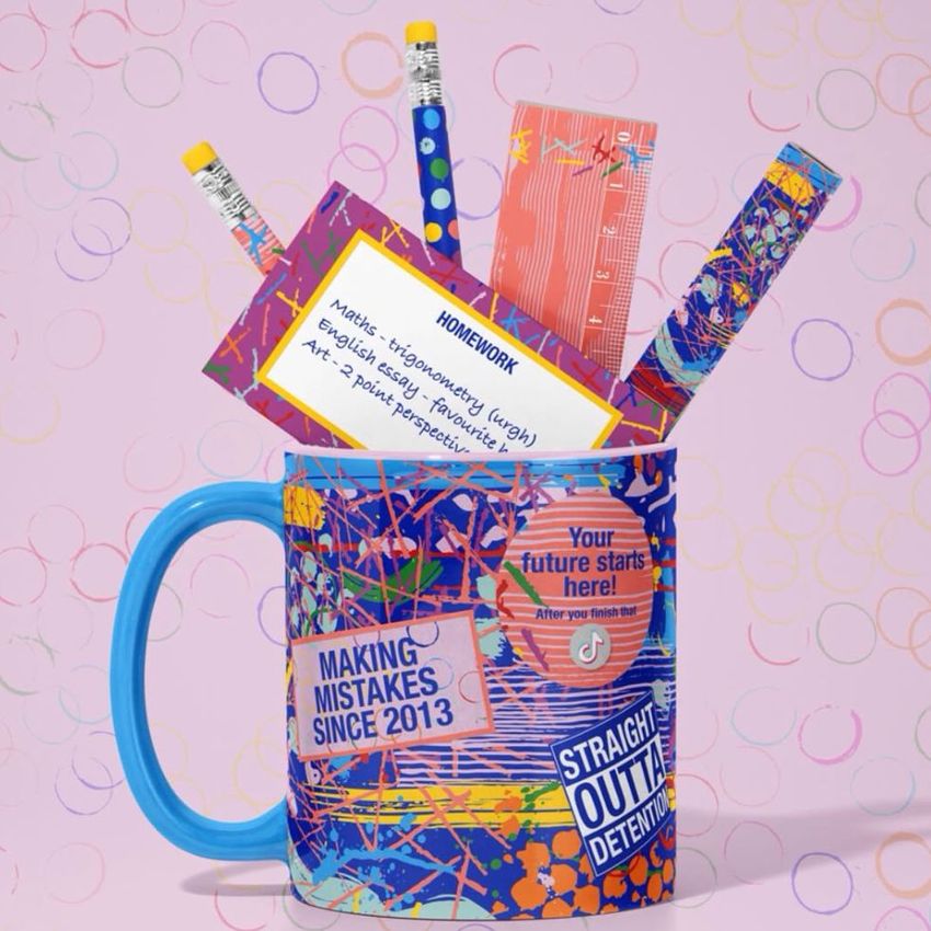 Mug mockup with a colorful abstract pattern holds pencils, a ruler, and pens, set against a pastel pink background with circles.