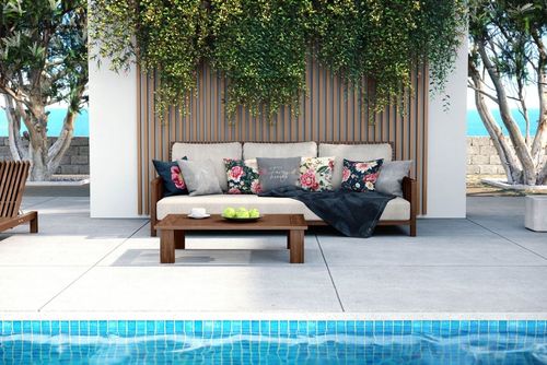 PSD mockup scene featuring a patio sofa with decorative pillows, surrounded by lush plants and poolside tiles.