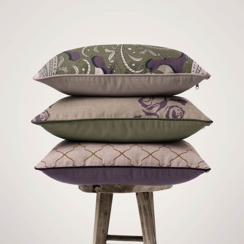 Stack of three reversible piped cushions mockup with different floral and geometric patterns, placed on a rustic wooden stool.