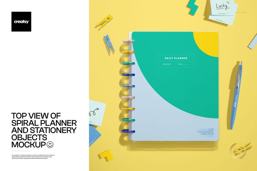 Spiral planner mockup displayed from above with pens, sticky notes, and paper clips arranged on a yellow surface.