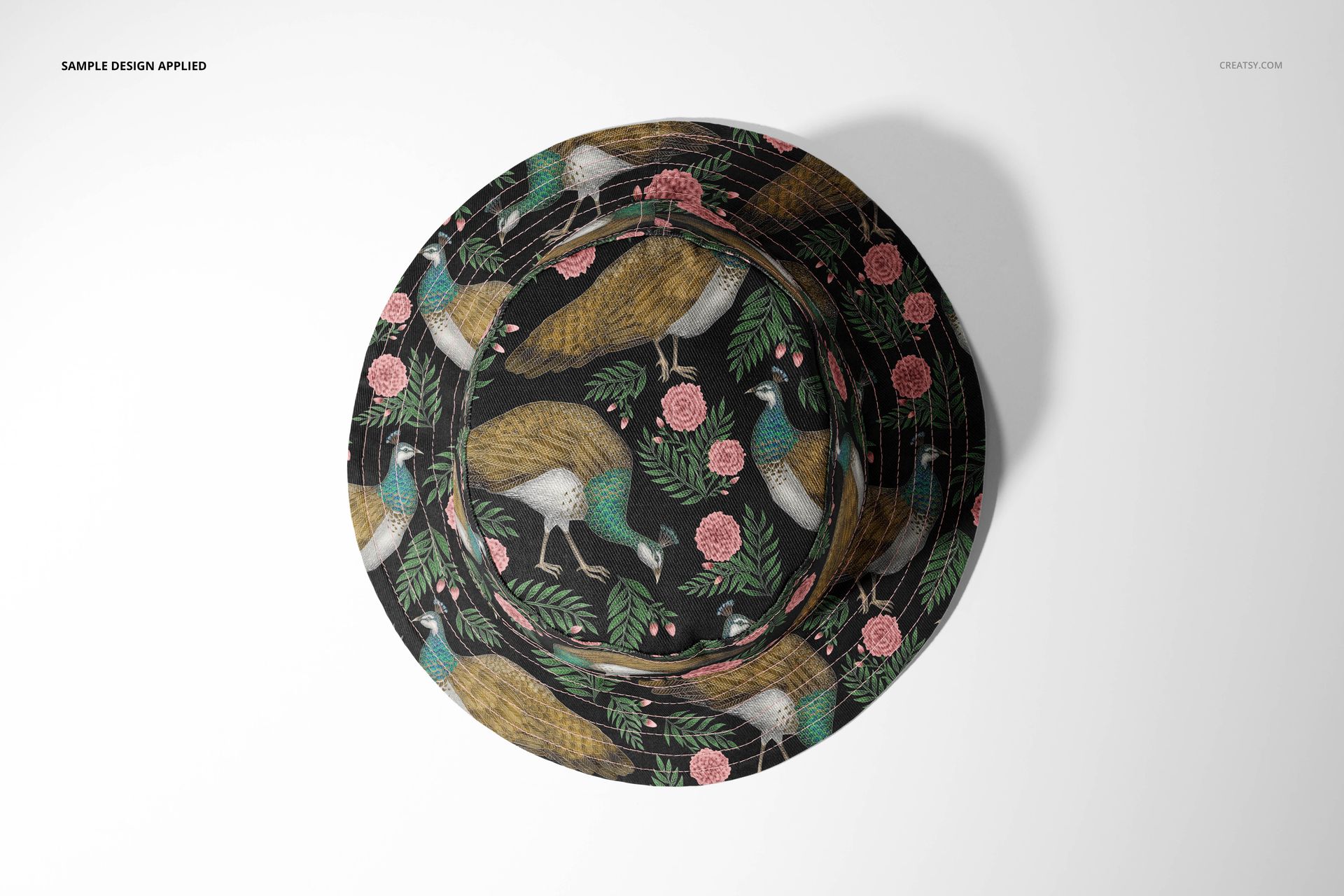 Reversible bucket hat mockup shown from above, decorated with colorful birds and floral elements on a black base.