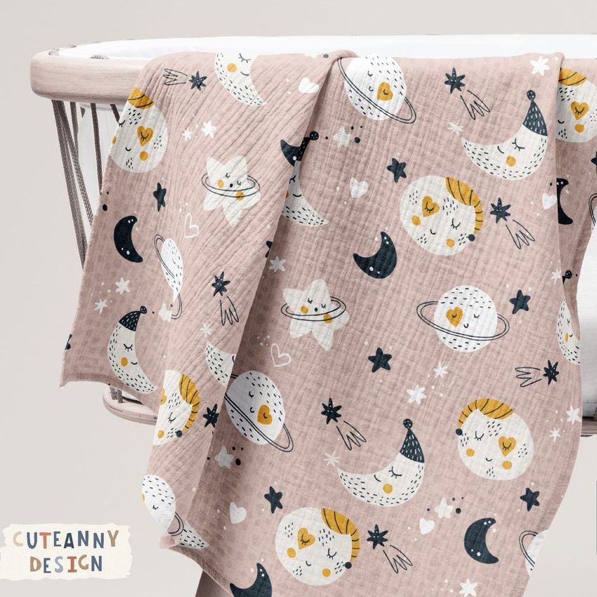 Crinkle muslin swaddle blanket mockup draped over a white crib, featuring a pink fabric with moon and planet illustrations.