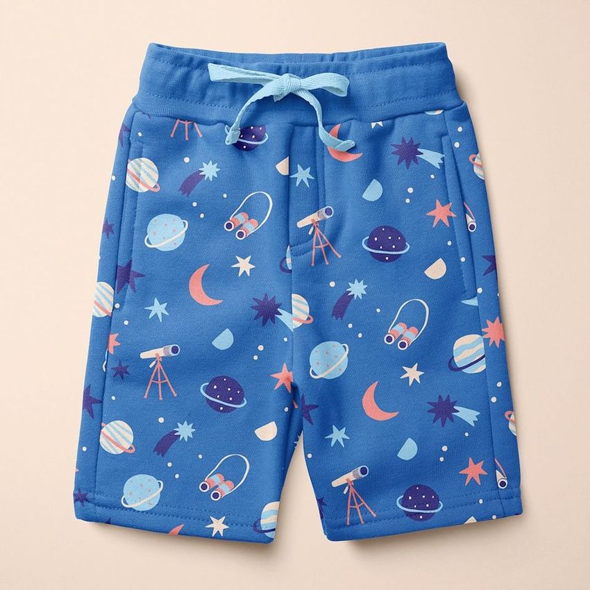 Kids cotton shorts mockup featuring a blue fabric with a playful space-themed pattern of planets, stars, and telescopes on a beige background.