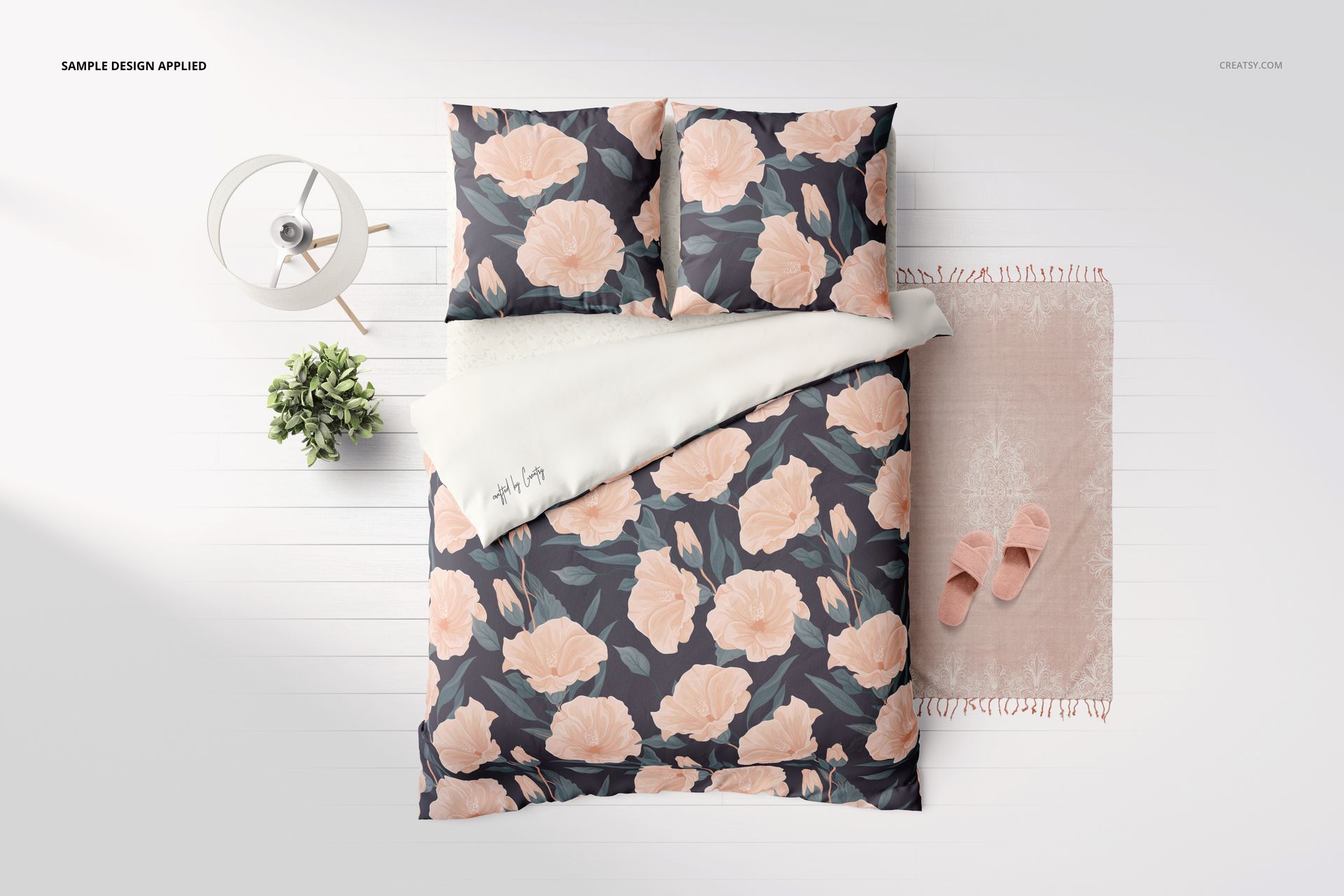 Bedding mockup with euro pillows, floral design, white sheet, and rug with slippers on a white wooden floor.
