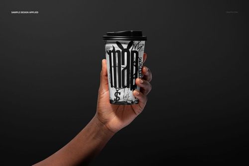 PSD mockup of a paper coffee cup in hand, displaying a striking black and white pattern with a solid dark backdrop.