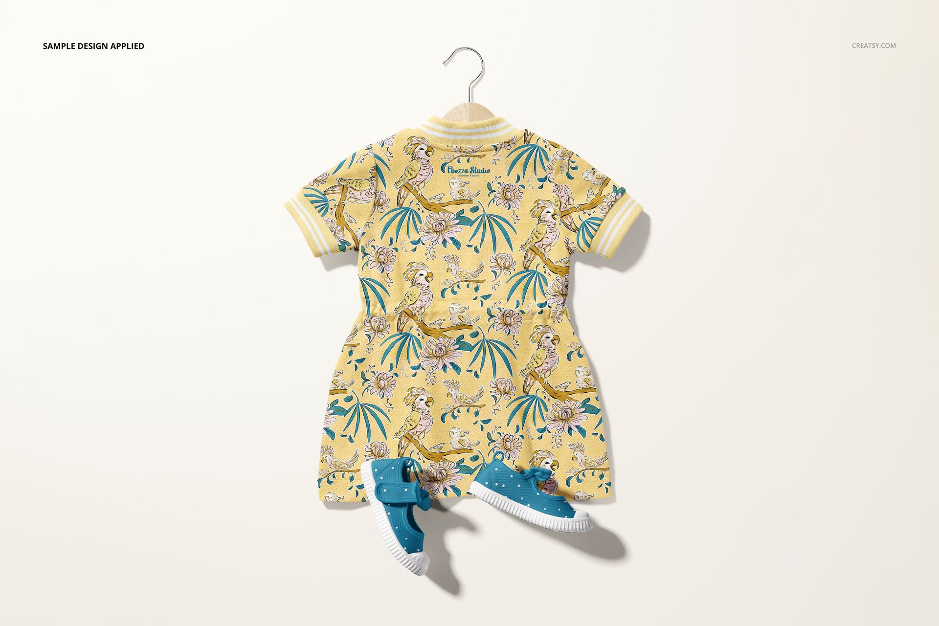 Baby dress mockup featuring a colorful animal print design, displayed on a hanger with matching blue baby shoes.
