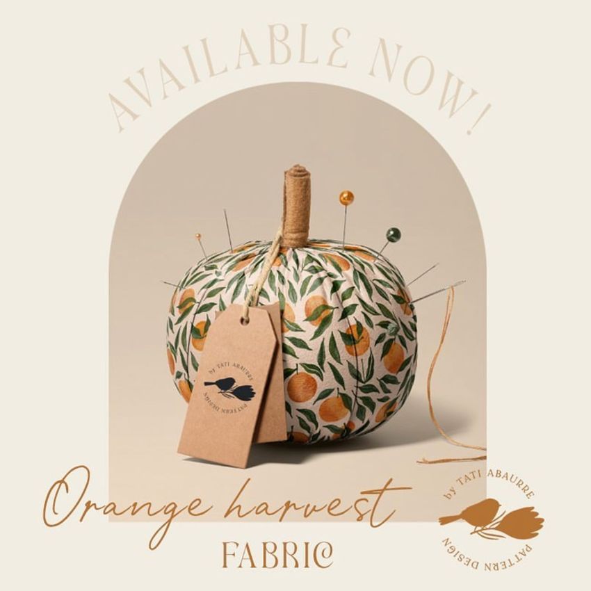 Fabric pumpkin mockup featuring a patterned pumpkin with orange and green leaves, pins, and a brown tag on a beige background.
