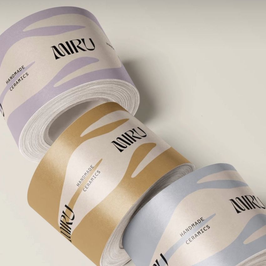 Three mailing box mockups with custom printed labels in beige, lavender, and gray, arranged diagonally on a light surface.